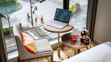 A modern room with a laptop on a small table, a chair with a cushion, a coffee mug, and a vintage camera.