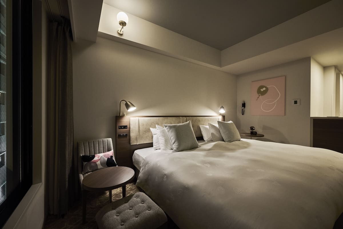 A hotel room with a large bed, bedside tables, a round table, and a small seating area.