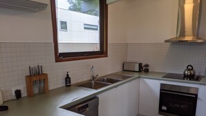 Keittiössä on valkoiset kaapit, ruostumattomasta teräksestä valmistettu pesuallas, leivänpaahdin ja vedenkeitin.