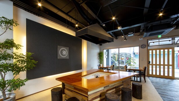 Una sala de reuniones moderna con una mesa de madera, sillas y una planta en maceta.