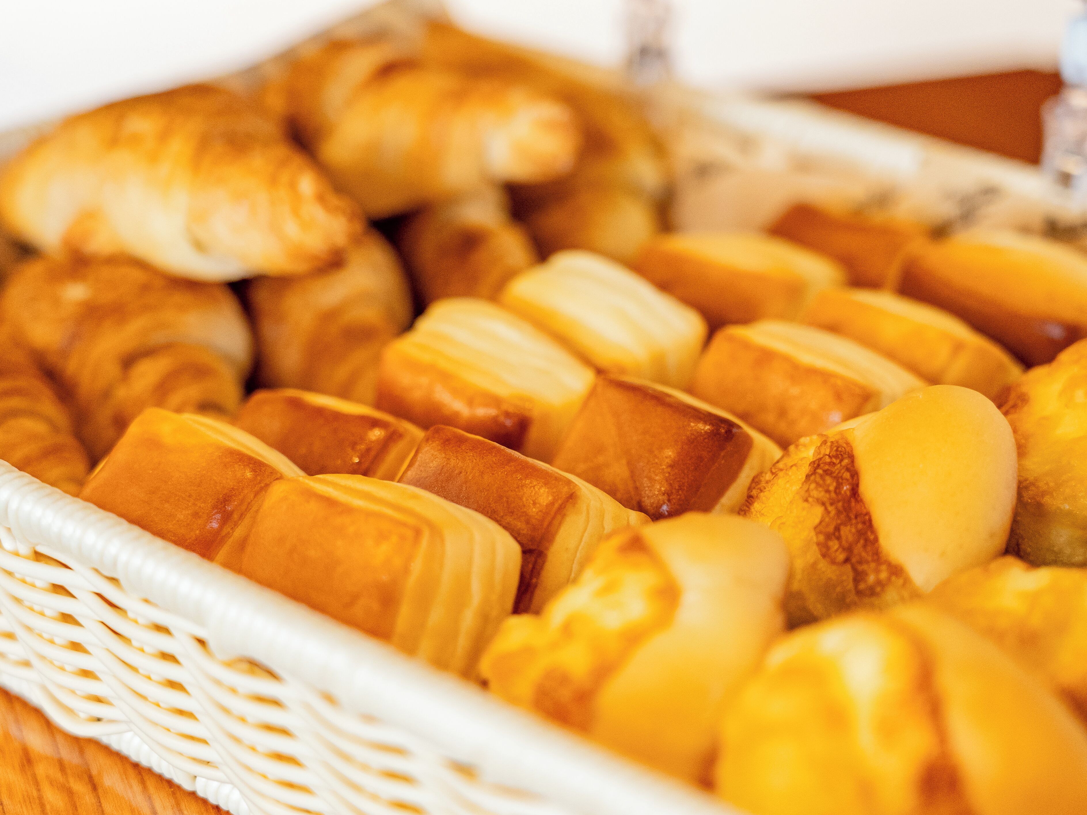 A basket of assorted pastries, including croissants and bread rolls.
