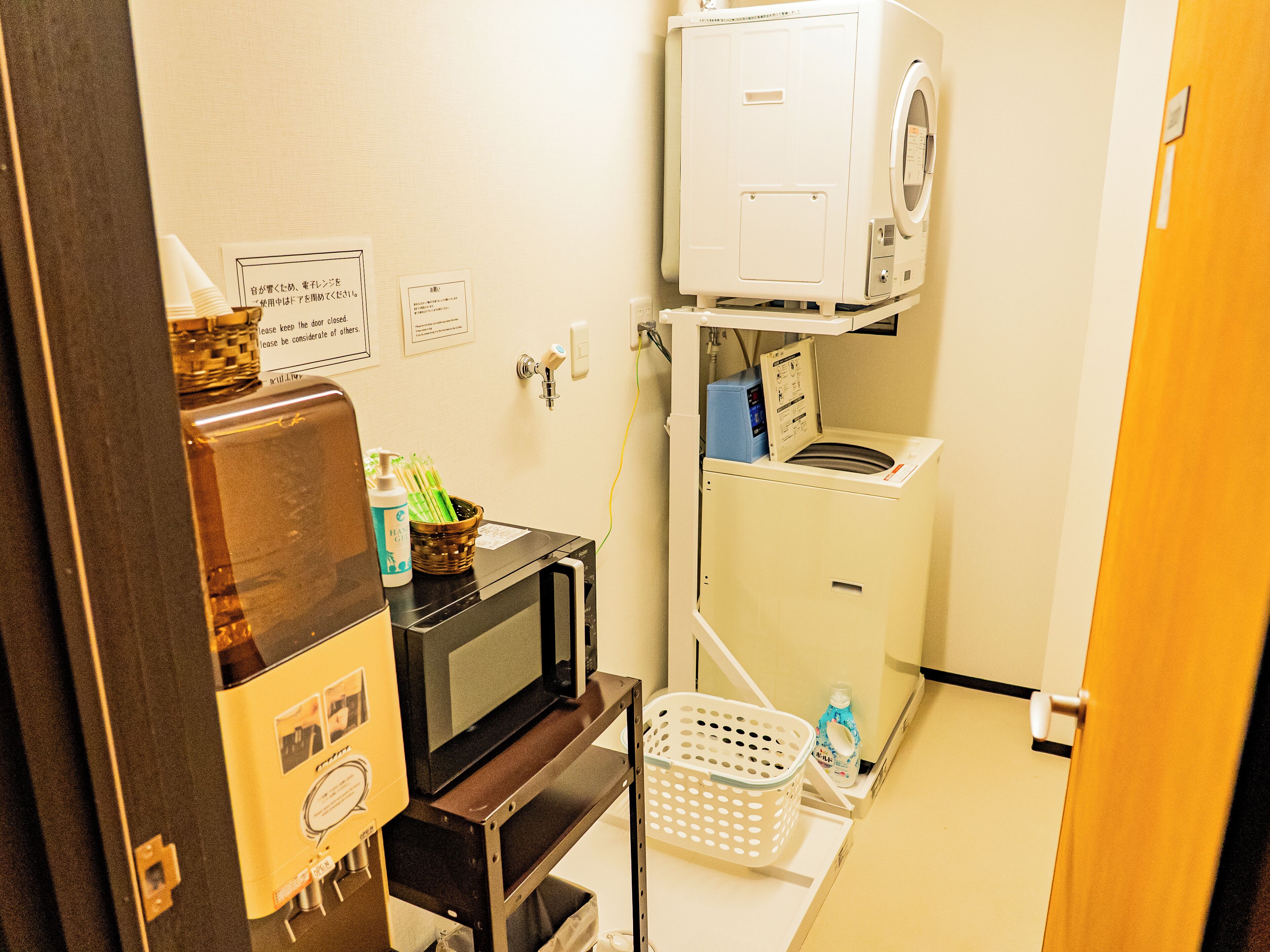 Een praktische wasruimte met een wasmachine, een magnetron en een kleine koelkast.