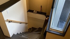 Una escalera con barandilla, una lámpara y una ventana que ofrece vistas al exterior.