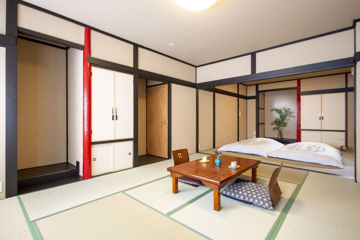 A traditional Japanese room with tatami flooring, a low wooden table, and a futon bed.