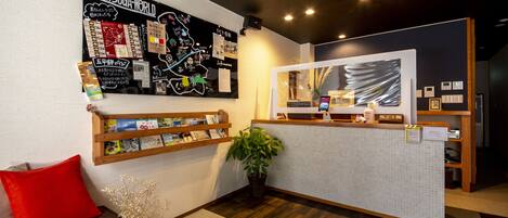 A reception area with a map, information board, wooden shelves, a plant, and a red pillow.