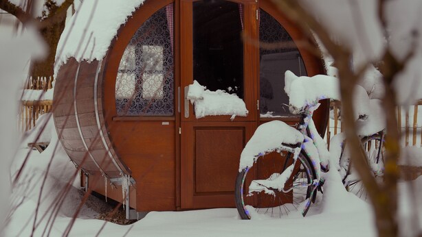 A wooden cabin with a snow-covered porch and a bicycle. - Vacation home (Eisenberg)