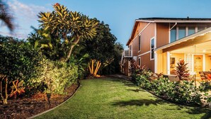 Un jardín bien cuidado con césped, diversas plantas y una construcción de madera con balcón.