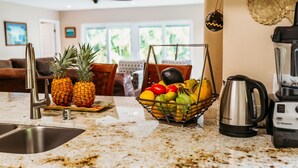 Una cocina con encimera de granito, una cesta de frutas, un hervidor y una licuadora.