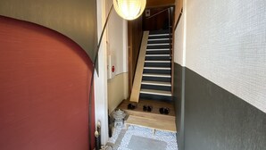 A staircase with a wooden handrail and a red wall on one side. - Yado KUKAI Shin Imamiya (Osaka)