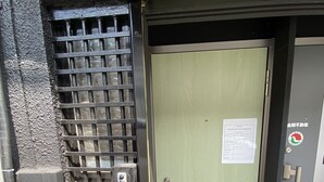 A door with a security keypad and a card reader, a metal grid window, and a sign with text. - Yado KUKAI Shin Imamiya (Osaka)