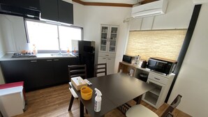 A compact kitchen with a dining area, featuring a microwave, stove, and cabinets. - Yado KUKAI Shin Imamiya (Osaka)