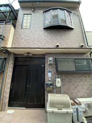Un edificio residencial con un portón negro, un ventanal saliente y un buzón.