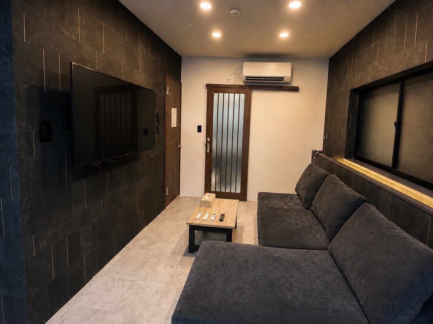 A modern interior with a sofa, a small table, and a TV mounted on the wall.