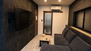 Un interior moderno con un sofá, una mesita y un televisor montado en la pared.