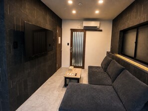 A modern interior with a sofa, a small table, and a TV mounted on the wall.