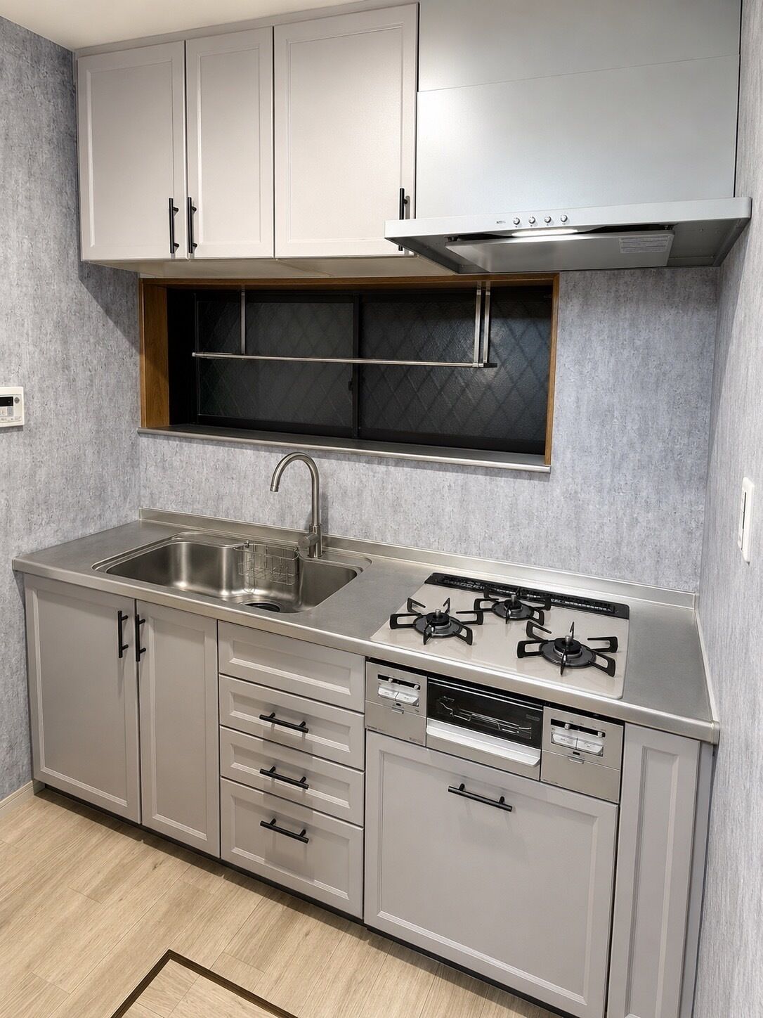 A modern kitchen with a stainless steel sink, gas stove, and built-in cabinets.