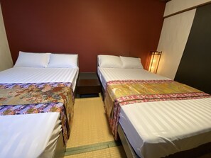 A hotel room with two single beds, each with a patterned bedspread, a small wooden nightstand, and a wall-mounted lamp. - Miyako Yado Matsu (Osaka)