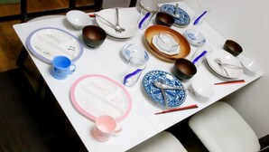 A dining table set with plates, bowls, cups, and cutlery.