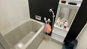 A bathroom with a bathtub, a shower, and a vanity with toiletries.