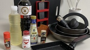 A kitchen counter with various cooking utensils, bottles of condiments, and a frying pan.