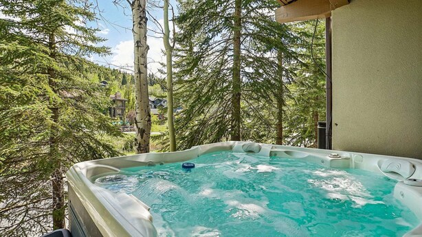 A hot tub with a view of tall trees and a building in the background.