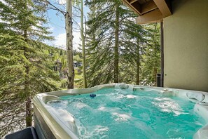 A hot tub with a view of tall trees and a building in the background.