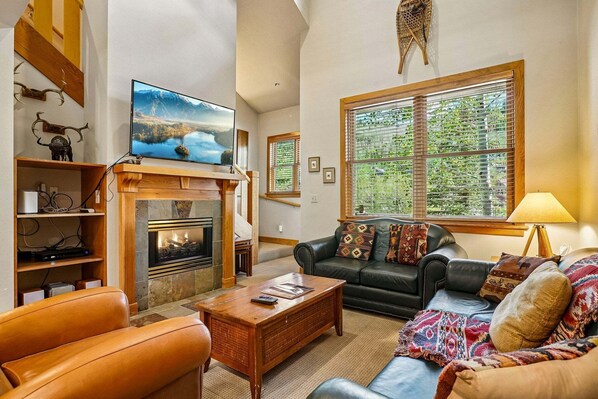 A living room with a fireplace, leather sofa, and a television on a wooden stand.