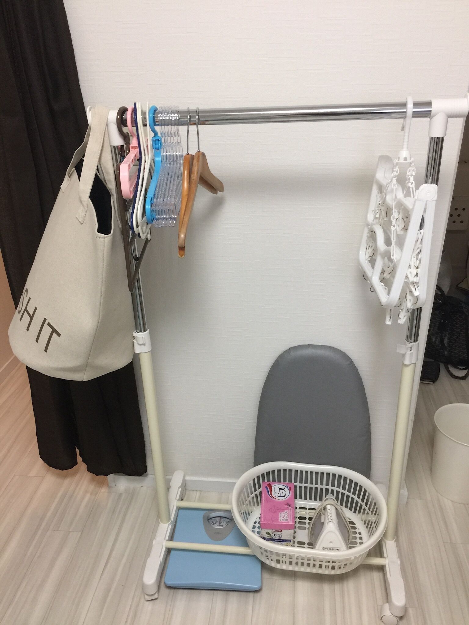 A bathroom with a white shower caddy, a scale, a basket with toiletries, and a towel hanging on a rack.