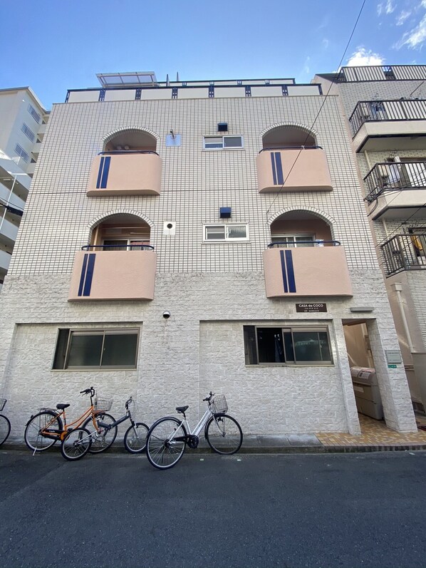 En byggnad med flera våningar, ett fasadbeklätt med kakel, balkonger och en skylt som visar att det är en bostadsfastighet.