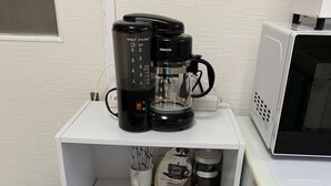 A kitchenette with a coffee maker, microwave, and storage shelves. - GOLDHOUSE Shinosaka 305 (Osaka)
