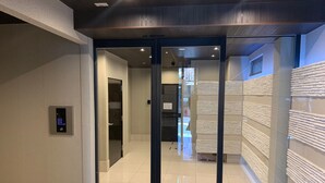 A modern hotel lobby with a digital keypad, a glass door entrance, and a tiled floor. - A-Style Matsu 601 (Osaka)