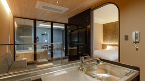Una habitación de hotel moderna con un espejo grande, un lavabo con escurridor, una cama y un televisor.
