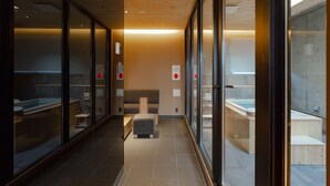 Un área de spa moderna con paredes de vidrio, techo de madera y sauna visible.