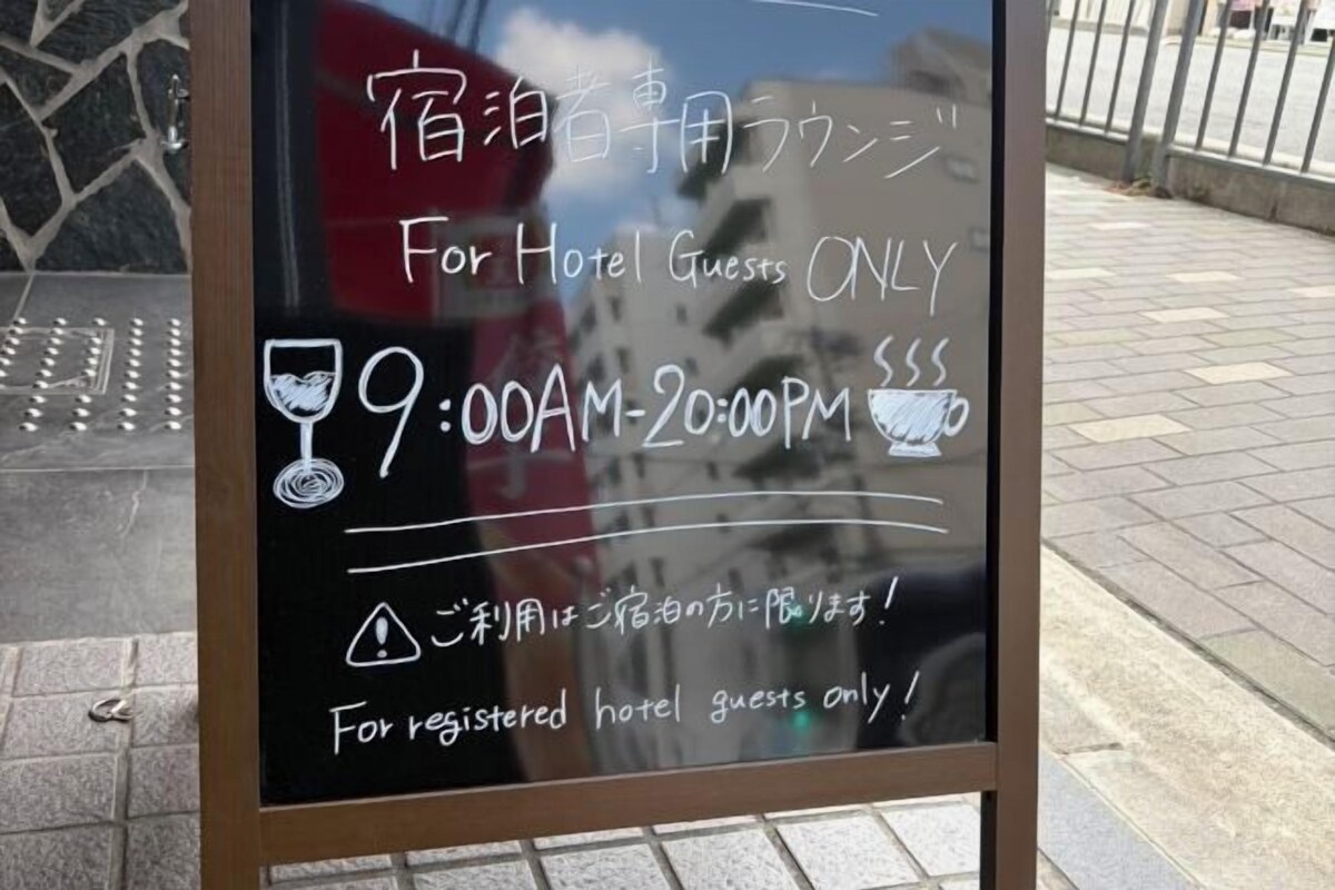 A sign with Japanese text and English translation for hotel guests, specifying hours of operation.