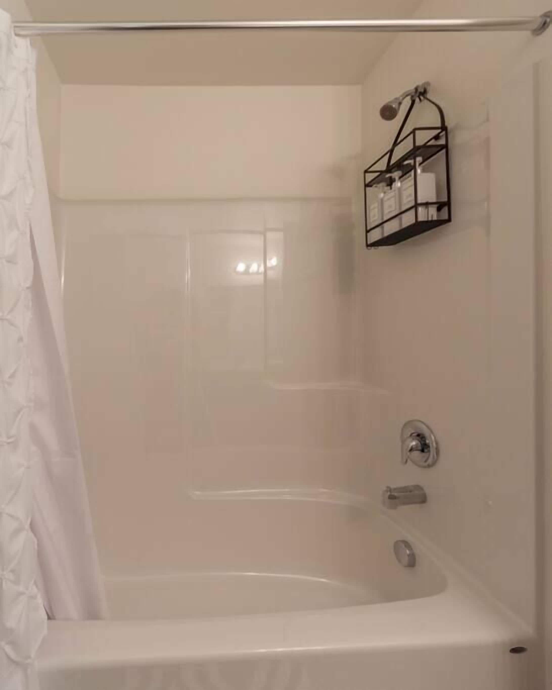 A bathroom with a bathtub, a shower, and a towel rack.