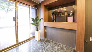 A reception area with a wooden reception desk, a large potted plant, and a sign that reads "DIAMOND HOTEL". - Diamond Hotel (Jinju)