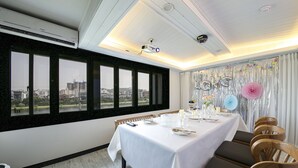 A dining area with a table set for four, large windows, and a view of the cityscape. - Diamond Hotel (Jinju)