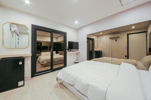 A modern bedroom with a large bed, a wardrobe with a sliding door, a small desk, and a mirror on the wall. - Boutique Hotel Super Rocket (Jinju)