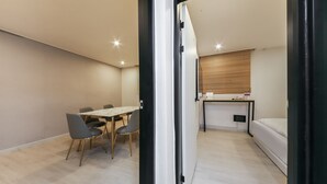 Een compacte kamer met een eettafel en stoelen, een kleine kitchenette en een bed.