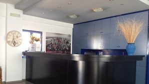 Un espace d’accueil avec un comptoir noir, une horloge et une grande affiche accrochée au mur.