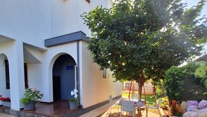 A white building with a covered patio and a small garden area with a table and chairs. - Apartment 418/952 (Istria - Valbandon), 1800m from the beach (Valbandon)