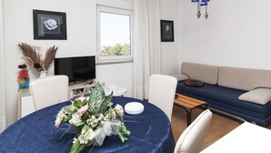 Ein modernes Wohnzimmer mit rundem Tisch, einer Couch und einem Fernseher.