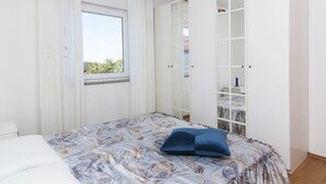 Ein Schlafzimmer mit Bett, einem Fenster mit Vorhängen und einem Kleiderschrank.
