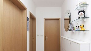 Ein Flur mit Holztüren, einem weißen Kommode, einem Spiegel und Regalen mit Stofftieren.