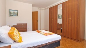 A bedroom with a bed, a wooden wardrobe, a wooden dresser, and a door leading to another room. - Apartment 727/1697 (Istria - Stinjan), 500m from the beach (Stinjan)