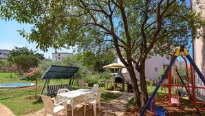 A patio with a table and chairs, a barbecue grill, a swing set, and a small pool. - Apartment 727/1698 (Istria - Stinjan), 500m from the beach (Stinjan)