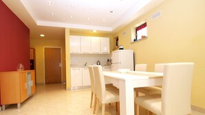 A modern kitchen with white cabinets, a dining table with chairs, and a refrigerator. - Apartment 727/1700 (Istria - Stinjan), 500m from the beach (Stinjan)