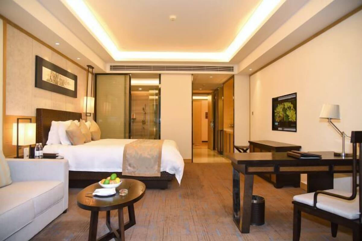 Habitación de hotel con cama, escritorio, silla, una mesita con un frutero y un sofá.