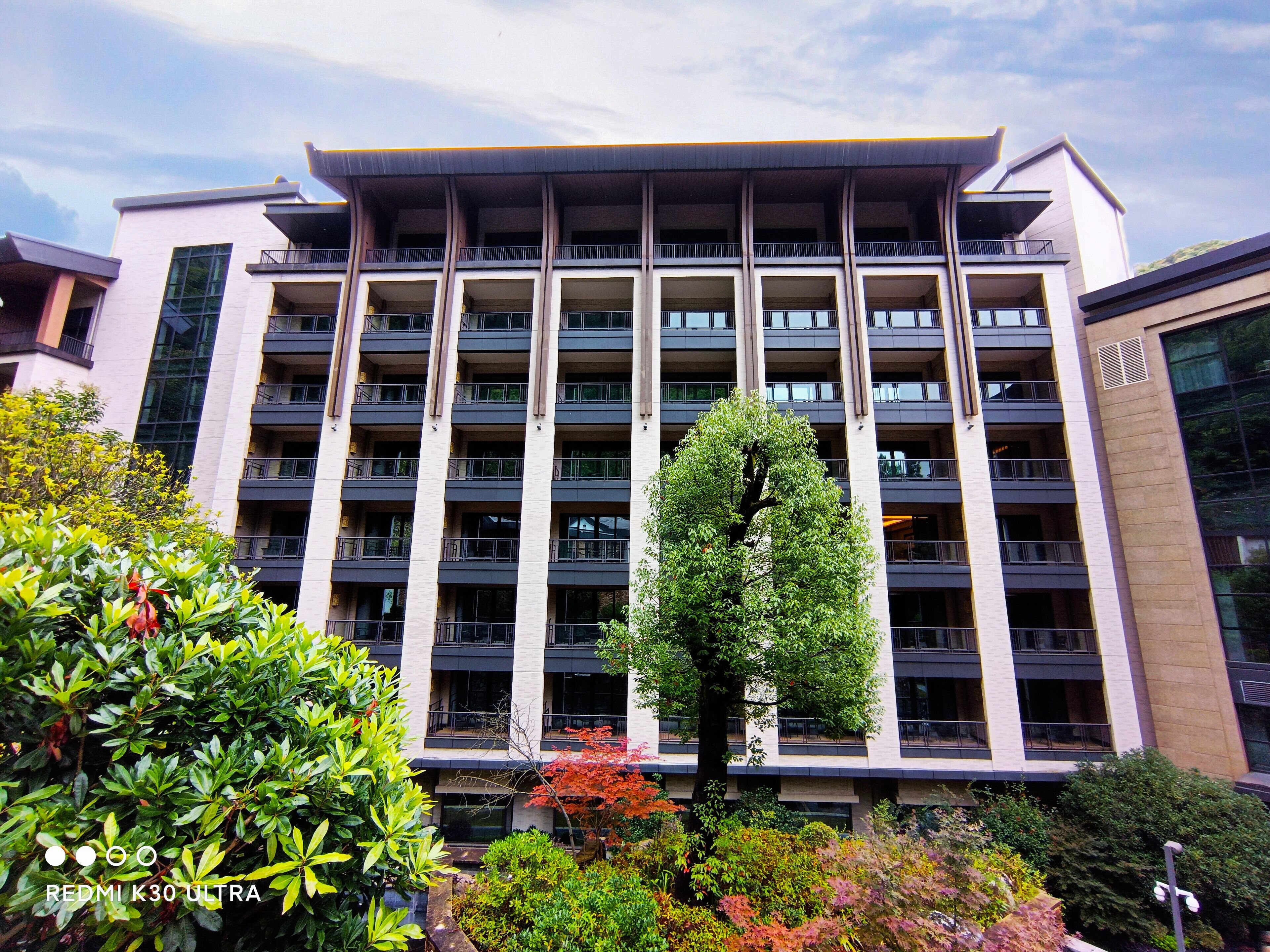 A multi-story building with a modern architectural design, featuring balconies and large windows.