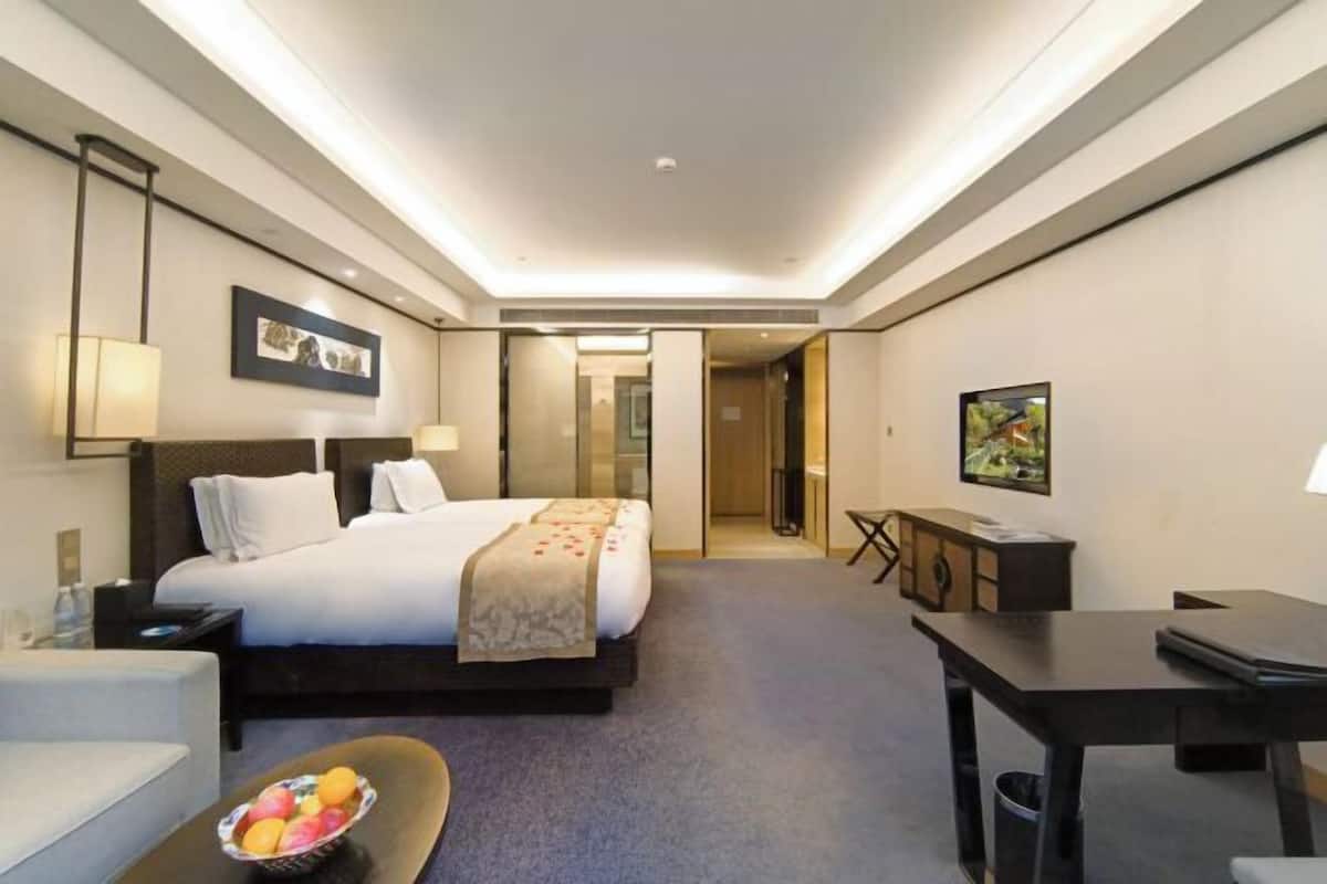 Una habitación de hotel moderna con una cama grande, mesitas de noche, un escritorio y una televisión.